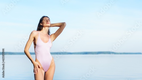 A sunburned young woman in a swimsuit poses against the background of the sea. Copy Space. © makedonski2015