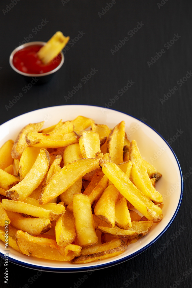 Homemade French Fries on a Plate on a black background, side view. Homemade French Fries on a Plate on a black background, side view.