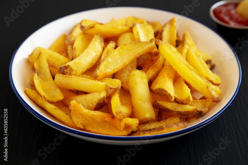 Homemade French Fries on a Plate on a black background, side view.