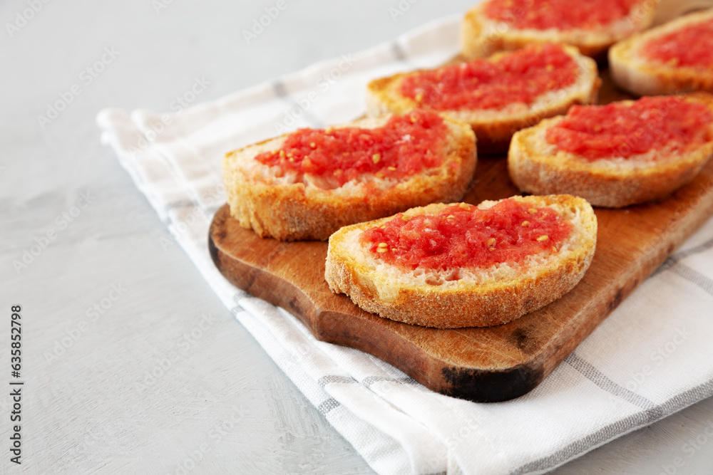 Homemade Pan Con Tomate (Tomato Toast) on a Rustic Wooden Board, side view. Copy space.