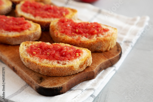 Homemade Pan Con Tomate (Tomato Toast) on a Rustic Wooden Board, side view. Copy space.