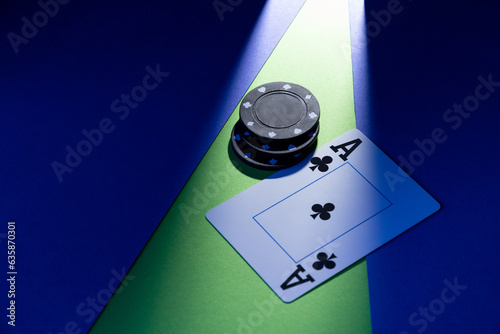 A plastic playing card lies on a blue-green background, next to three chips. photo