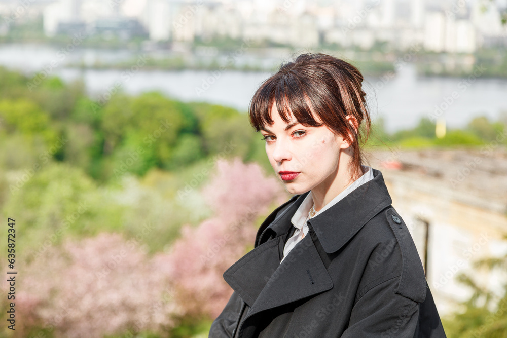 A beautiful girl drinks coffee at the table, in a raincoat, in a white shirt, in black trousers with suspenders A beautiful girl drinks coffee at the table, in a raincoat, in a white shirt, in black trousers with suspenders