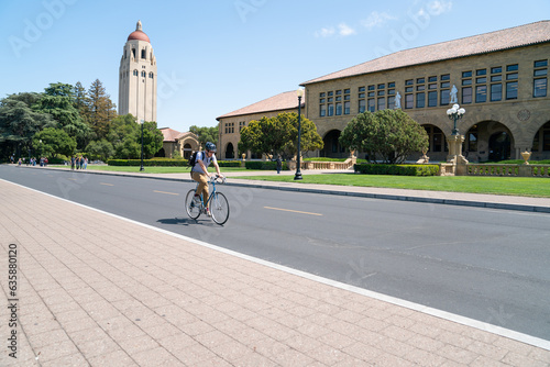 California, USA - May 15, 2018: view from a boulevard hoover tower among trees and school buildings against blue sky in distance on school campus with a man riding bike