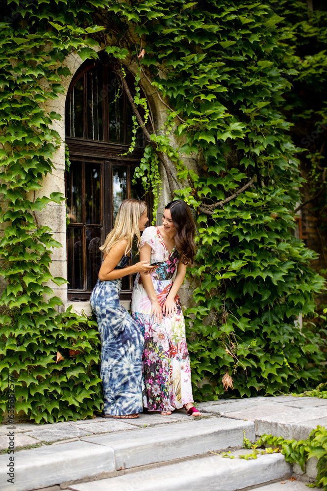 Pretty young women using mobile phone by the old house with ivy