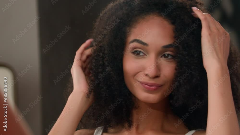 African American beautiful woman beauty routine in bathroom girl looking mirror reflection touching curly hair healthy haircare touch curls prepare in morning procedure hairdo shampoo result hairstyle