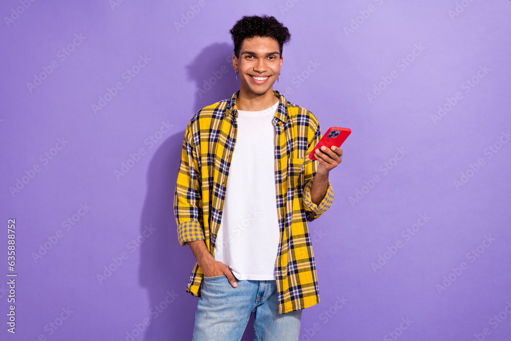 Photo of handsome positive guy with stylish earrings dressed checkered shirt hold smartphone read post isolated on purple color background Photo of handsome positive guy with stylish earrings dressed checkered shirt hold smartphone read post isolated on purple color background