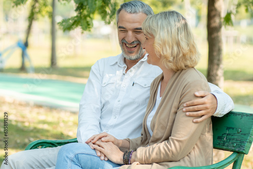 Happy elder love couple huge and smiling in romance sitting in park