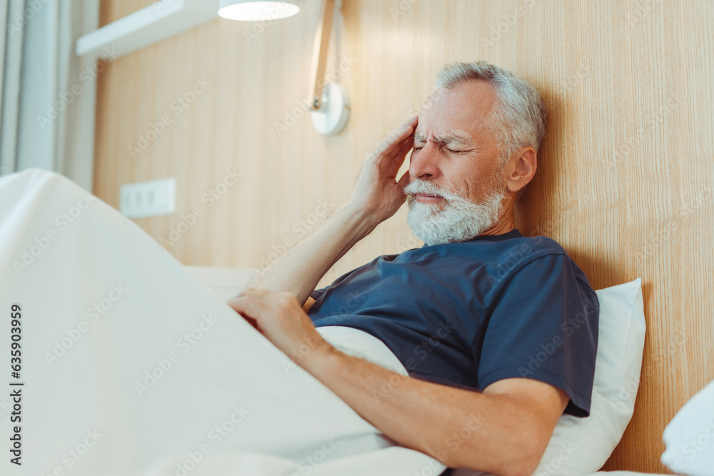 Obraz premium Sad tired senior man having headache, migraine, feeling bad lying in hospital bed. Pain, stress, medical treatment concept 