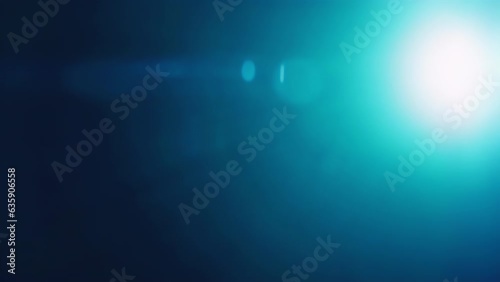 Real anamorphic lens flare leaks from light beam appearing from left and moving to right on black background for overlay.