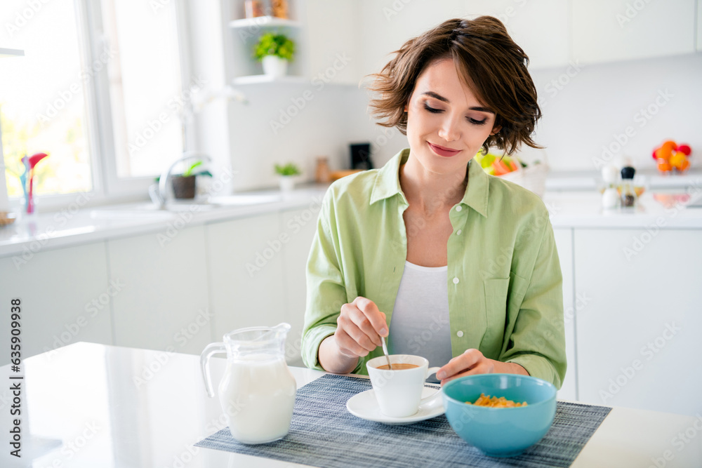 Photo of cute sweet girl wear green shirt enjoying fresh coffee eating breakfast indoors kitchen room Photo of cute sweet girl wear green shirt enjoying fresh coffee eating breakfast indoors kitchen room