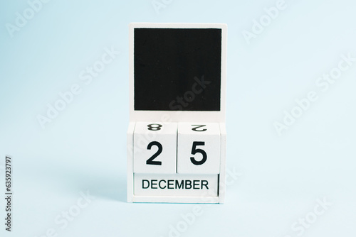 Christmas, wooden calendar with the date December 25 on a blue background with copy space. The concept of preparing for the celebration of Christmas and New Year and plans for the future.