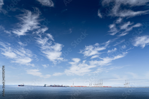 Wide angle freighters being loaded with coal shipped by rail by conveyer belt with water spraying for coal dust at Roberts Bank British Columbia. 