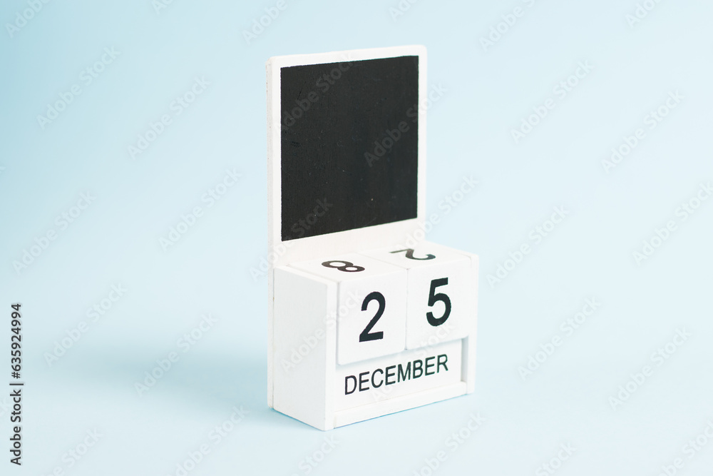 Christmas, wooden calendar with the date December 25 on a blue background with copy space. The concept of preparing for the celebration of Christmas and New Year and plans for the future. Christmas, wooden calendar with the date December 25 on a blue background with copy space. The concept of preparing for the celebration of Christmas and New Year and plans for the future.