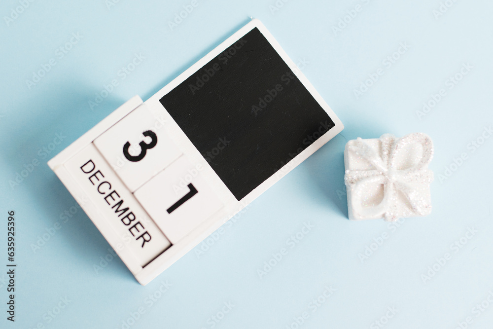 New Year, wooden calendar with the date December 31 on a blue background with decor, flatlay. The concept of preparing for the celebration of Christmas and New Year and plans for the future.