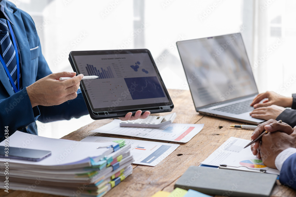 Group of confident business people point to report graphs and financial charts analyze market data, balance sheet, account, net profit to plan new sales strategies to increase production capacity.