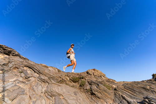 tourist girl with a backpack on her back climbs the mountain in summer