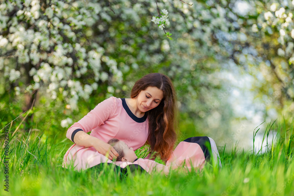 mother and daughter sit outdoors in a blooming garden mother and daughter sit outdoors in a blooming garden