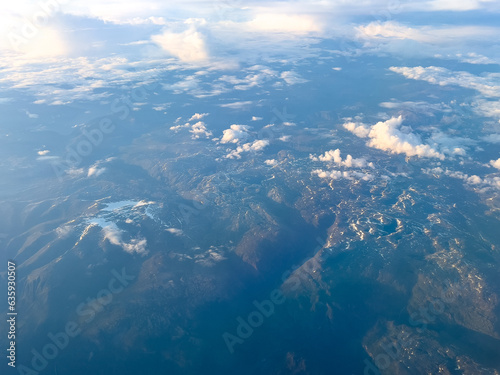 picture of mountains partially covered with snow Taken from a high angle on an airplane. Clouds partially covered the top of the mountain.