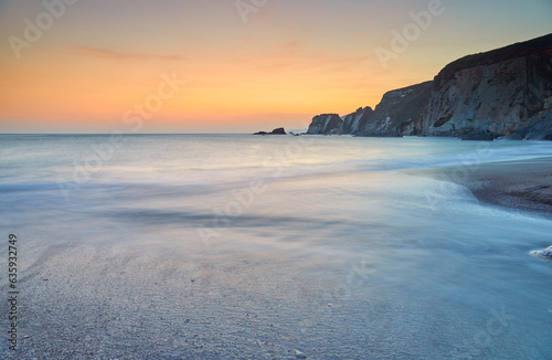 A dusk view of surf surging ashore at Ayrmer Cove, a remote cove near Kingsbridge, south coast of Devon, England, United Kingdom