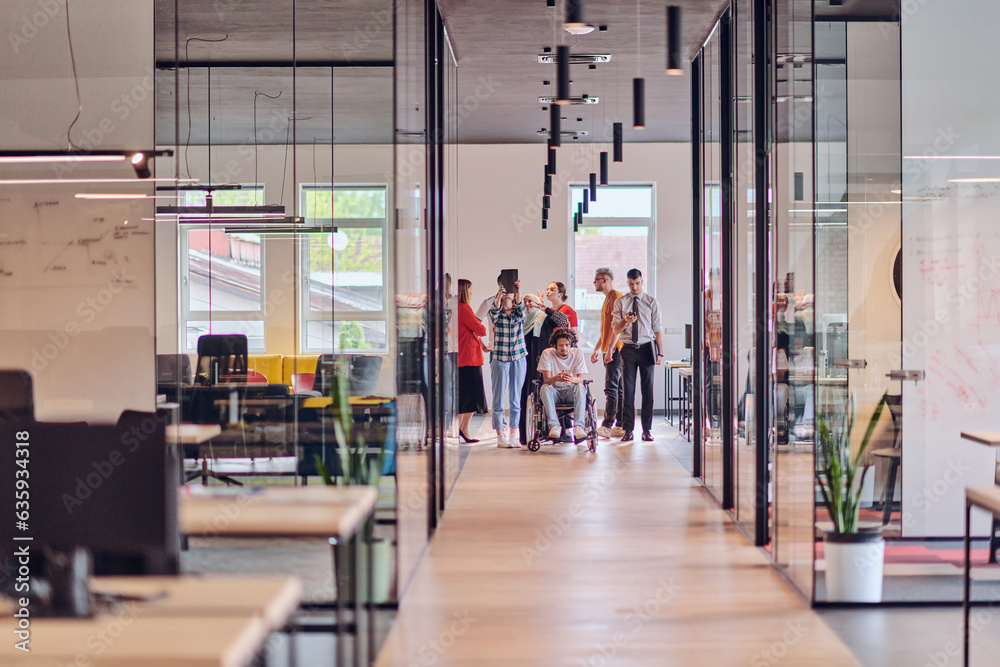 Obraz premium A diverse group of young business people congregates within a modern startup's glass-enclosed office, featuring inclusivity with a person in a wheelchair, an African American young man , and a hijab