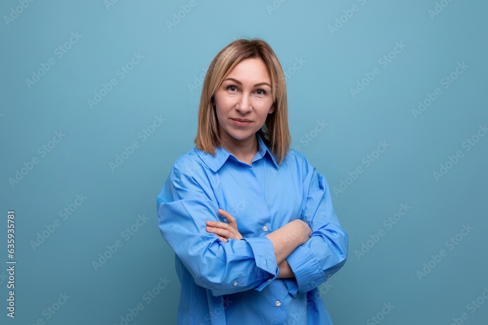 serious european blond woman folded her hands in front of her on a blue background with copyspace serious european blond woman folded her hands in front of her on a blue background with copyspace