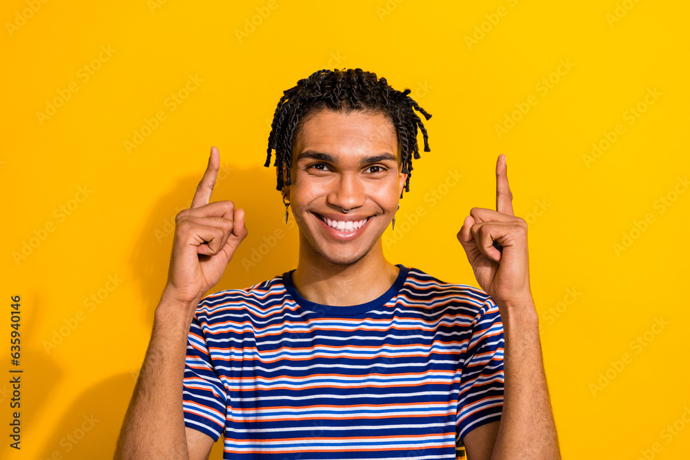 Photo of glad positive man wear trendy striped clothes arms presenting empty space black friday sale isolated on yellow color background