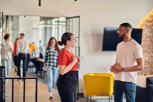 Young business colleagues, including an African American businessman, engage in a conversation about business issues in the hallway of a modern startup coworking center, exemplifying dynamic problem