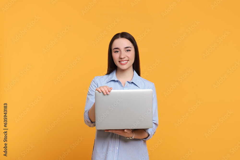 Smiling young woman with laptop on yellow background Smiling young woman with laptop on yellow background