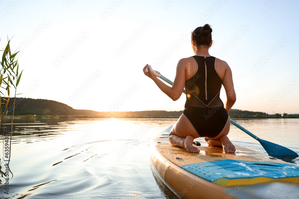 Ταπετσαρία Woman paddle boarding on SUP board in river at sunset, back view
