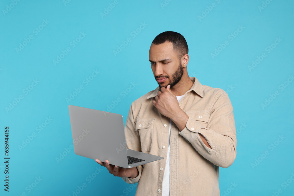 Thoughtful young man with laptop on light blue background Thoughtful young man with laptop on light blue background