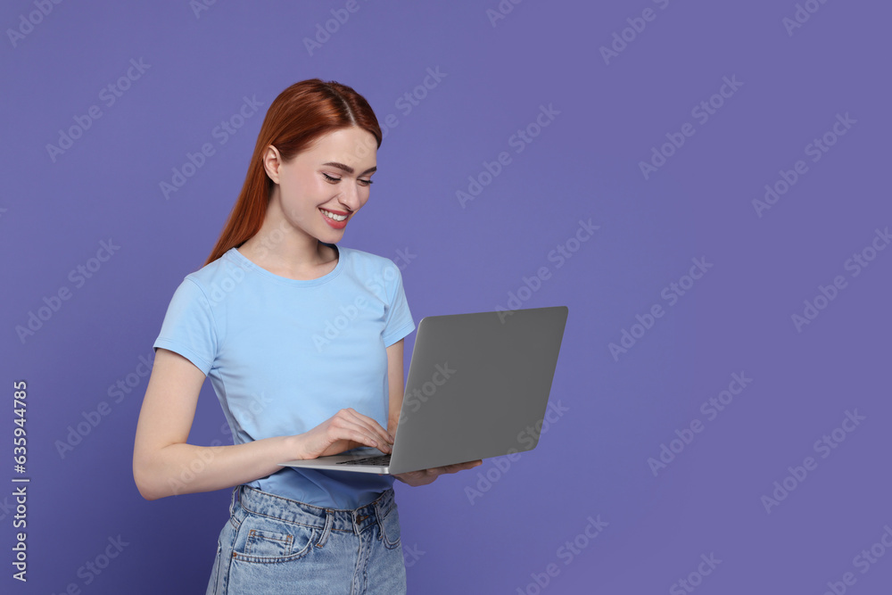 Smiling young woman working with laptop on lilac background, space for text Smiling young woman working with laptop on lilac background, space for text