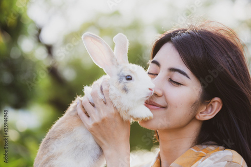 relationships of cheerful rabbit and happy young human girl, Asian woman holding and carrying cute rabbit with tenderness and love. Friendship with cute easter bunny. Happy of Easter's Day © chokniti