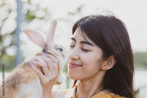 relationships of cheerful rabbit and happy young human girl, Asian woman holding and carrying cute rabbit with tenderness and love. Friendship with cute easter bunny. Happy of Easter's Day © chokniti
