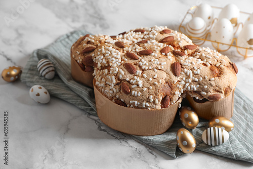 Delicious Italian Easter dove cake (Colomba di Pasqua) and decorated eggs on white marble table