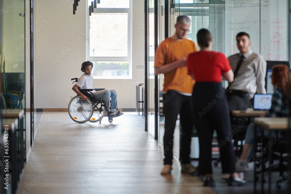 A diverse group of colleagues engages in a discussion about business challenges within a modern coworking startup center, while in the background, their wheelchair-bound colleague symbolizes