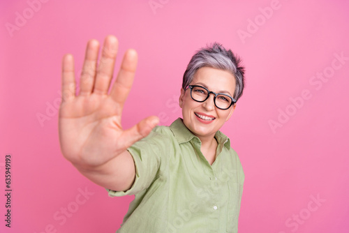 Closeup photo of pensioner good mood woman cheerful friendly showing five number waving palm hello symbol isolated on pink color background