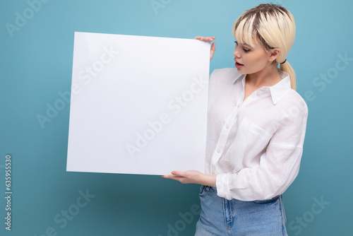 young pretty blond student woman dressed in a white blouse demonstrates her study project on a blackboard with a mockup