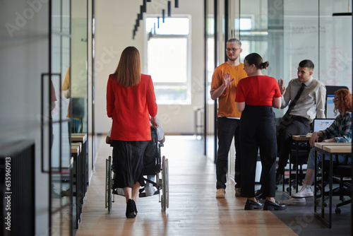 A group of young business people in a modern glass-walled office captures the essence of diversity and collaboration, while two colleagues, including an African American businessman in a wheelchair © .shock