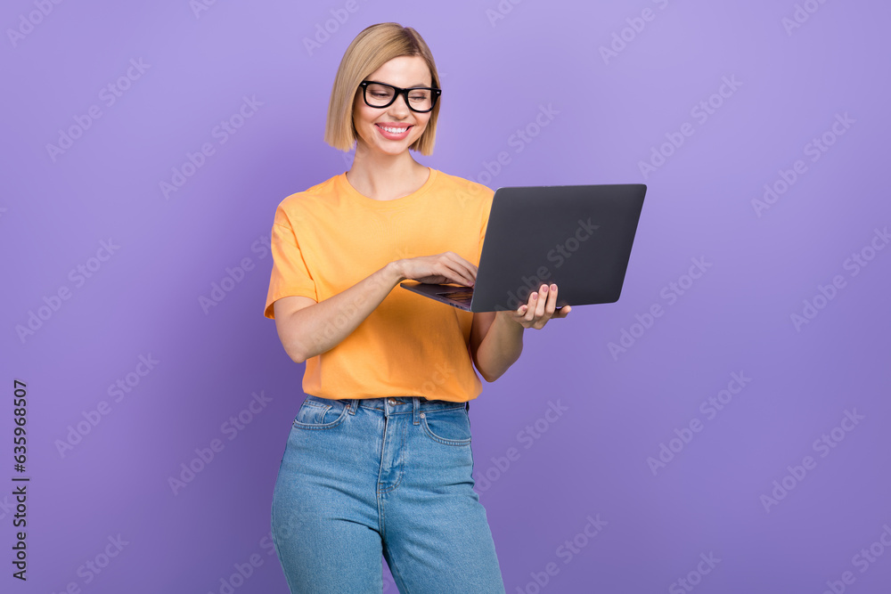 Portrait of satisfied clever girl with bob hairdo dressed stylish clothes look at laptop typing email isolated on violet color background Portrait of satisfied clever girl with bob hairdo dressed stylish clothes look at laptop typing email isolated on violet color background