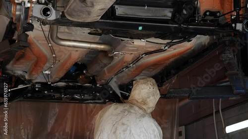 Work at the bus station. Washing car with water from a gun under high pressure. The service employee very carefully washes the bottom of the car, going over all the nodes and elements of the body 4k