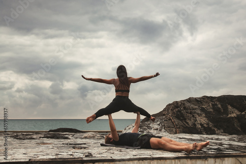 Fit young couple doing acro yoga for healthy lifestyle on tropical coast
