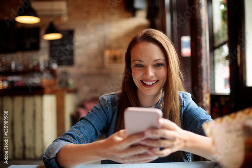 Young caucasian woman using a smart phone while in an indoor cafe in London UK