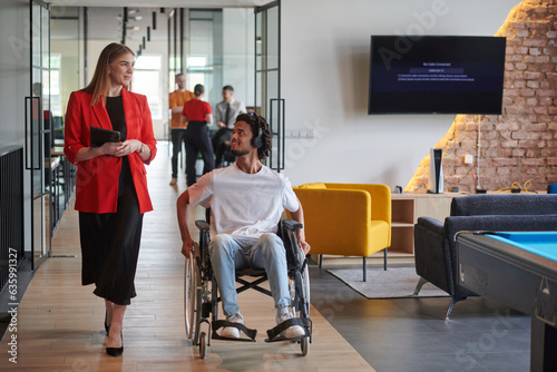 A group of young business people in a modern glass-walled office captures the essence of diversity and collaboration, while two colleagues, including an African American businessman in a wheelchair