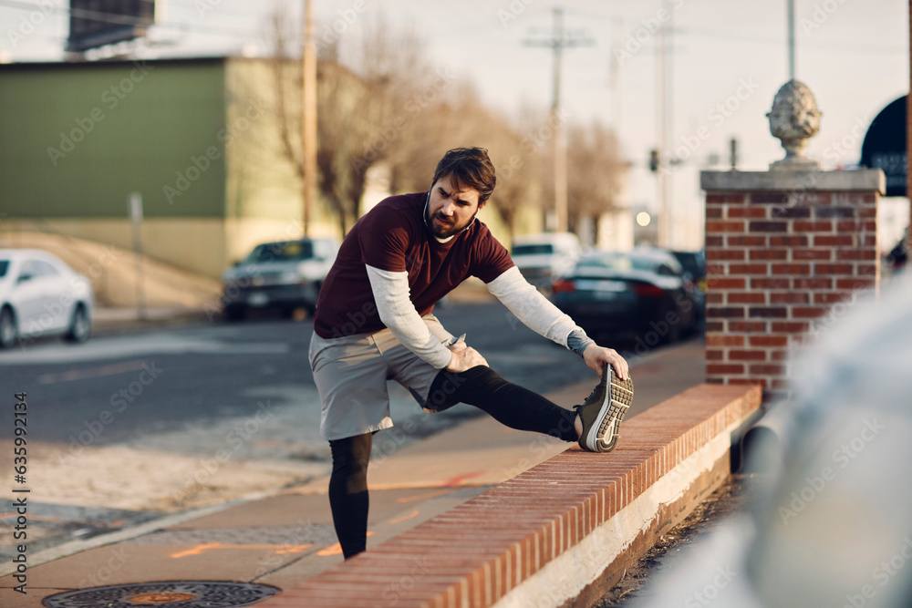 Young caucasian man stretching before jogging and exercising on a sidewalk in St Louis USA