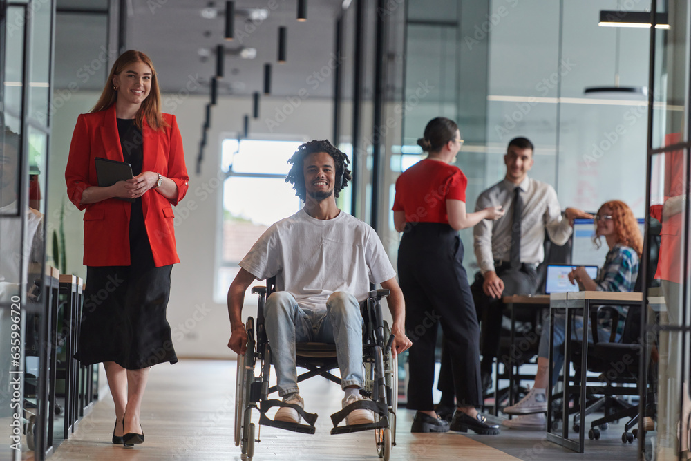 A group of young business people in a modern glass-walled office captures the essence of diversity and collaboration, while two colleagues, including an African American businessman in a wheelchair A group of young business people in a modern glass-walled office captures the essence of diversity and collaboration, while two colleagues, including an African American businessman in a wheelchair