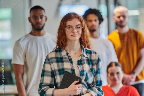 A diverse group of business people walking a corridor in the glass-enclosed office of a modern startup, including a person in a wheelchair and a woman wearing a hijab, showing a dynamic mix of