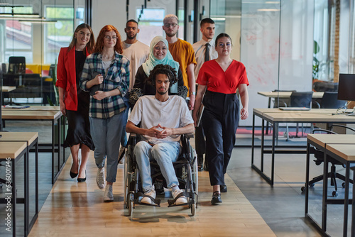 A diverse group of young business people walking a corridor in the glass-enclosed office of a modern startup  including a person in a wheelchair and a woman wearing a hijab  showing a dynamic mix of
