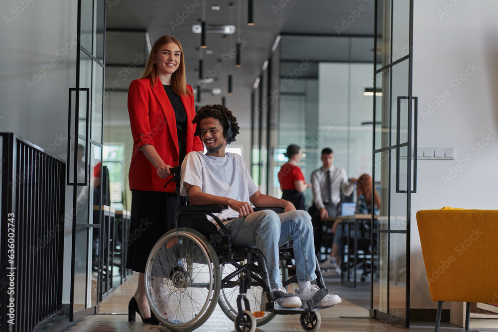 A group of young business people in a modern glass-walled office captures the essence of diversity and collaboration, while two colleagues, including an African American businessman in a wheelchair A group of young business people in a modern glass-walled office captures the essence of diversity and collaboration, while two colleagues, including an African American businessman in a wheelchair