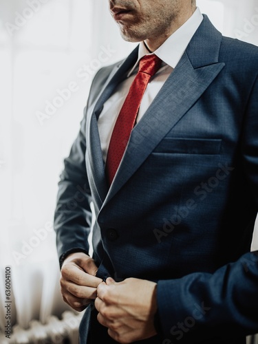 Vertical shot of an attractive male in a blue suit and red tie